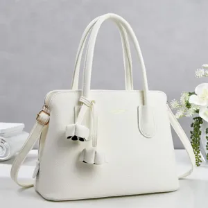 Detail view of the elegant white pebbled leather handbag with double handles and gold hardware.
