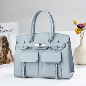 Sac a main en cuir bleu clair avec poches avant et serrure argentees pour le travail quotidien.