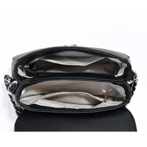 Détail intérieur du sac à bandoulière en cuir noir avec compartiments zippés et doublure.