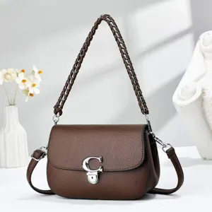 Détail de sac à bandoulière en cuir marron, poignée chaîne tressée et fermoir métallique.