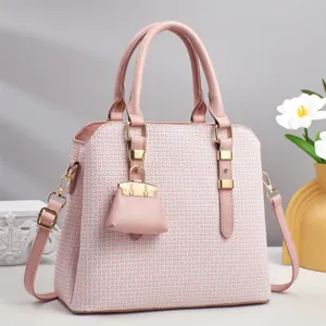 Gros plan sur les détails du sac à main monogrammé rose avec quincaillerie dorée et charm.