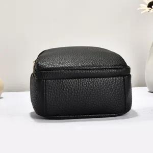 Détail d'un mini sac à dos noir en cuir grainé avec texture fine et fermeture à glissière.