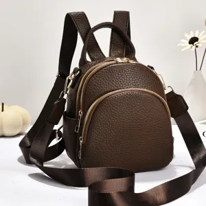 Mini sac à dos en cuir marron en détail avec double fermeture éclair et bretelles.