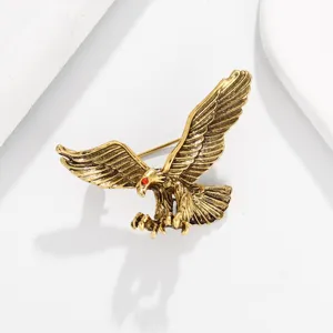 Gros plan d'une broche aigle doree style vintage avec un detail d'oeil de cristal rouge.