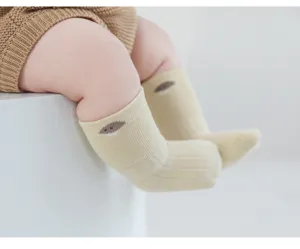 Gros plan détaillé de douces chaussettes bébé en coton avec de charmants motifs brodés.
