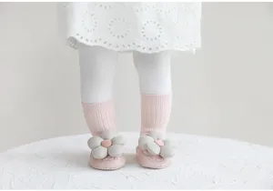 Primo piano dettagliato di scarpe calzini rosa per neonati con adorabili fiori 3D.