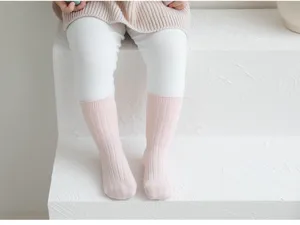 Primer plano de calcetines de canalé rosa para niños sobre escalones blancos limpios.