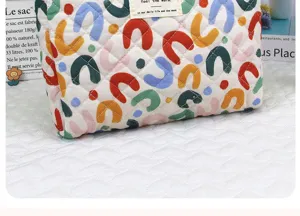 Quilted cosmetic bag with colorful U-shaped pattern, portable makeup storage pouch for daily use.