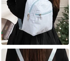 Detail view of the light blue seersucker backpack showing texture and dual zipper compartments.