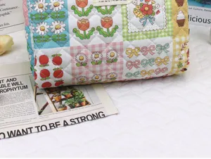 Quilted cosmetic storage bag with cute floral and bow patchwork prints, portable travel organizer.