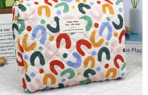 Detailed view of quilted cotton makeup pouch with colorful abstract arch print and cute label.