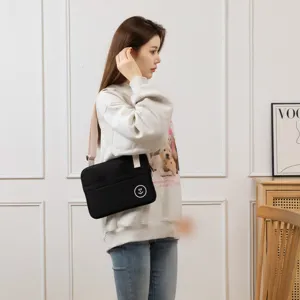 Detail shot of a black tablet shoulder bag with adjustable strap and smiley face logo in use.