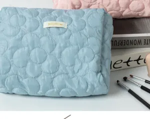Blue quilted floral cosmetic bag featuring fluffy texture, ideal for makeup storage and travel use.