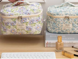 Quilted cosmetic bag detail view, portable floral makeup pouch with durable zipper and handle.