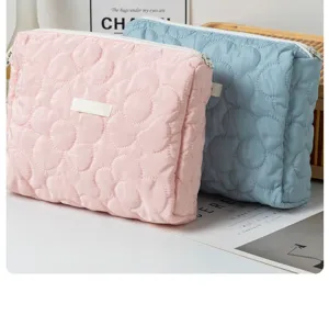 Close-up view of quilted floral cosmetic bags in pink and blue with soft padded texture.