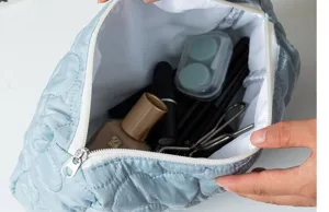 Detail view of light blue quilted cosmetic pouch, showing interior capacity and storage features.