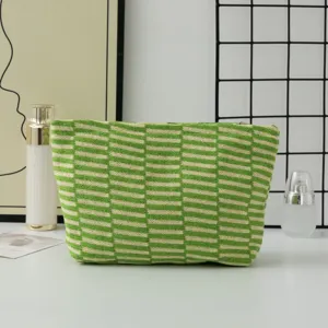 Detailed view of a stylish green and white knitted makeup bag, featuring textured stripe design.