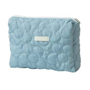 Light blue quilted cosmetic bag with stylish floral pattern, portable storage pouch for women.