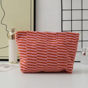 Close-up detail of knitted makeup pouch with orange pink stripe checkered pattern texture.