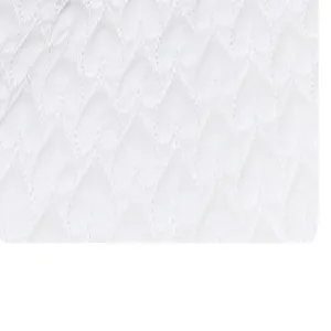 Close-up fabric detail of white quilted cosmetic bag showcasing soft stitched heart pattern.