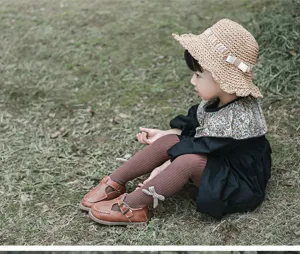 Vue détaillée de collants à nœud pour bébés filles avec chaussures en cuir sur herbe.