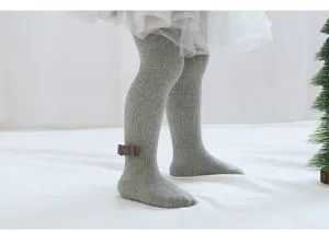 Baby grey ribbed tights detail, close-up of cute bow decoration on ankle, soft cotton.