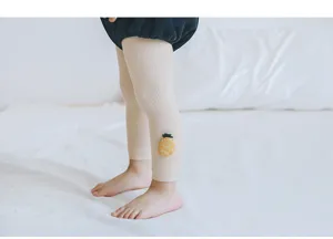Gros-plan de leggings pour bébé côtelés beige avec jolie broderie d'ananas sur la cheville.