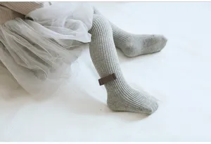Detailed close-up shot of grey ribbed baby tights with cute ankle bow decoration for toddlers.
