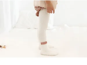 Detailed view of white ribbed baby tights featuring a cute pink ankle bow for cold days.