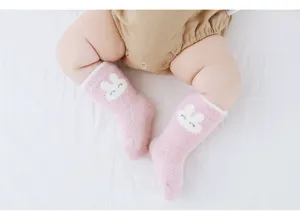 Vue détaillée de chaussettes en peluche pour bébé en rose avec joli motif de lapin blanc.