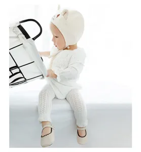 Dettaglio leggings neonata in rete bianca, collant di cotone traspirante con cappello.