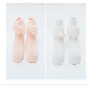 Vue détaillée de jolies chaussettes à volants pour bébé nouveau-né en coton rose et blanc.