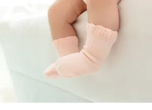 Detailweergave van zachte roze babysokken met delicate gebreide kantranden voor comfort.