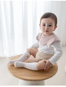 Detail shot of cute striped baby knee-high socks on infant sitting on a wooden stool.