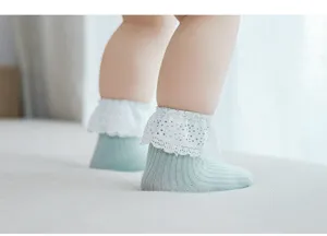 Détail de chaussettes côtelées vert clair pour bébé avec volant en dentelle blanche, coton doux.