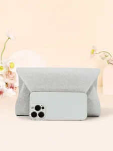 Gros plan sur la texture pailletée argentée scintillante et la taille compacte de la pochette.