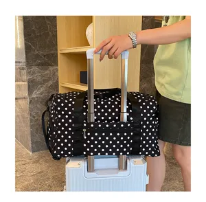 Grand sac de voyage cabine à pois avec sangle pour valise, idéal pour femmes en déplacement.
