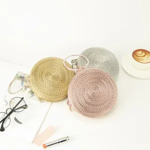 Detailed shot of handmade woven round clutch bags in gold, silver, and rose gold colors.