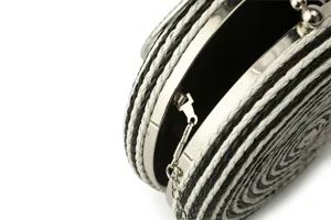 Detailed close-up of a black and white woven round evening clutch bag with metal frame.