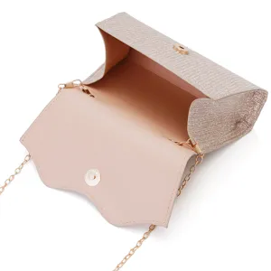 Detailed view of champagne glitter evening clutch bag with gold chain strap and magnetic clasp.