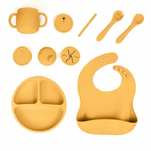 Set de repas en silicone pour bébé avec assiette divisée, bavoir, tasse, cuillère et fourchette.