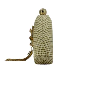 Side view of woven straw evening clutch bag with crystal flower and metal tassel detail.