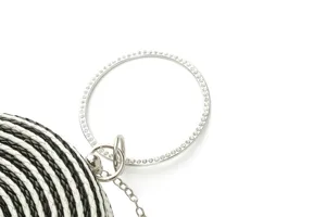 Close-up detail of the black and white woven round evening bag with crystal rhinestone handle.
