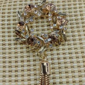 Close-up view of the sparkling rhinestone floral clasp and chic gold tassel on the woven bag.