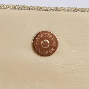 Vue détaillée du bouton pression aimanté en métal sur une élégante pochette de soirée pour femme.