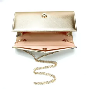 Gold metallic clutch bag detail view, elegant evening purse with chain strap and magnetic snap closure.