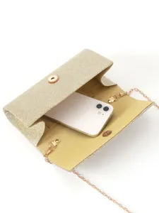 Detailed view of the gold glitter clutch bag showing its spacious interior with a phone.