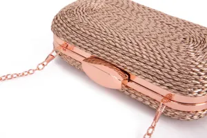Detailed close-up of rose gold woven clutch bag, featuring metallic frame and chain strap.