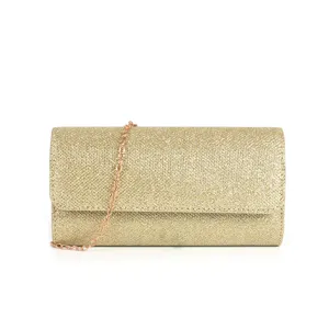 Gros plan détaillé du sac clutch de soirée doré scintillant avec une fine lanière de chaîne.