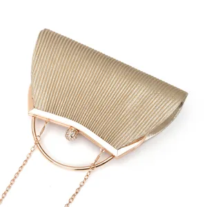 Detail view of gold pleated evening clutch bag with metallic round handle and rhinestone clasp.